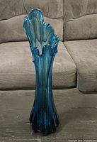 Full view of teal hand-blown glass vase showing color gradient and ruffled rim