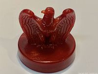 Front view of red glass eagle paperweight on circular base