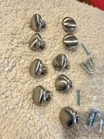 Front view of eight brushed nickel knobs with screws