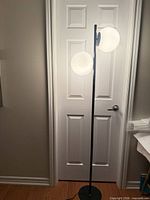 Lamp illuminated showing two frosted glass globes and black metal pole and base