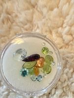 Top view of assorted loose gemstones in clear case
