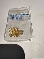 Plastic sleeve labeled Genuine Citrine containing loose oval yellow gemstones