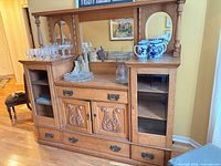 Front view of oak sideboard showing mirror, carved doors, drawers, and side compartments