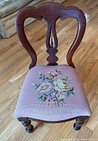 Balloon-back chair showing wood frame and floral needlepoint seat