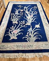 Full view of rectangular blue floral rug with border and fringe