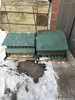 Two green metal bird feeders side by side showing roofs, wire hangers and overall condition