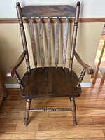 Front view of dark brown spindle-back armchair showing seat, back slats, arms and turned legs