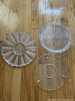 Three clear glass platters laid on wood floor