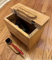 Full view of wooden shoe shine box open, brush and polish tins visible
