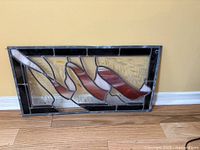 Horizontal stained glass panel with red ribbon on amber glass