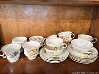 Group of assorted teacups and saucers on shelf