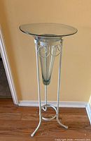 Full view of metal pedestal stand with glass vase inserted