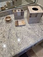 All four stone bathroom accessories displayed on countertop