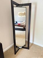front view showing full-length mirror within dark wood frame