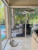 Full view of arc floor lamp beside sliding glass doors showing base, arcing arms, and pool outside