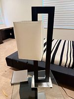 Full lamp on glass table showing frame, shade, base, cord