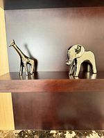 Elephant and giraffe figurines displayed together on shelf