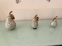 Full view of the three pear-shaped sculptures on glass surface