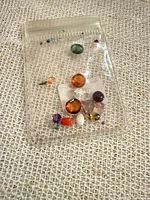 Front view of plastic bag showing assorted gemstones of various colors and shapes