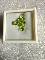 Group of light green faceted stones in display box