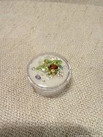 Top view of mixed loose gemstones inside plastic container