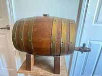 Right side view of oak barrel on stand showing brass-tone hoops and spigot