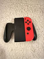Front view showing red Joy-Con inserted into black grip, left Joy-Con missing