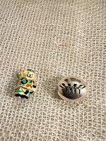 Front view of both charms showing camouflage bear and silver Beatles bead