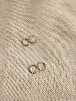 Four small silver-tone hoop earrings on fabric