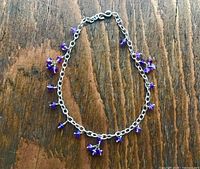 Anklet on wooden surface showing chain and amethyst drops