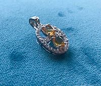 Side view of silver pendant showing citrine stones and halo