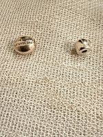 Front view of both sterling silver charm beads on fabric, showing text engraving on larger bead