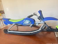 Left side view of blue Thunder Rider snow sled scooter showing seat, frame, skis and front steering assembly