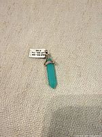 Front view of turquoise/aqua crystal point pendant charm with tag attached