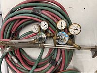 Coiled large twin hoses with regulators and torch handle attached