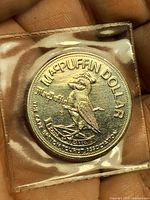 Obverse of MacPuffin Dollar in sleeve, puffin design visible