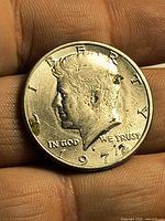 Obverse of 1972 Kennedy Half Dollar held between fingers