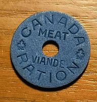 Obverse of blue Canada meat ration token on wood surface