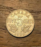 Reverse of 1930 Canada 5 cent coin showing denomination, maple leaves and date