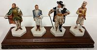 Full view of four figurines mounted on wooden base with plaque