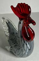 front left view of rooster showing red comb, clear tail, mottled grey body