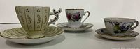 Three miniature teacup and saucer sets side by side