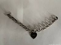 Full view of bracelet laid flat showing chain, heart tag and toggle clasp