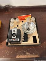 Open box showing Brownie Hawkeye camera, flash unit, six flashbulbs, internal insert