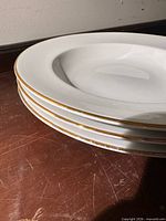 Stack of white porcelain bowls showing gold rim detail