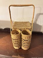 Front view of wicker picnic basket showing handle, lid and dual bottle holders