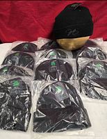 Twelve packaged black North Aware beanies with one displayed on mannequin head