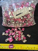 Sealed bag of rose rhinestones with label, loose stones and ruler for scale