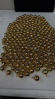 Large quantity of gold-tone hollow brass ball charms spread out