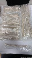 Multiple bags of faux pearl strands on tabletop